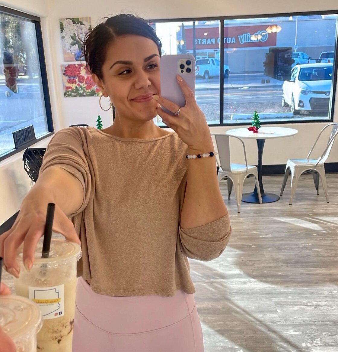 Owner Kssandra Chavez inside Casa Grande Nutrition holding two protein coffees